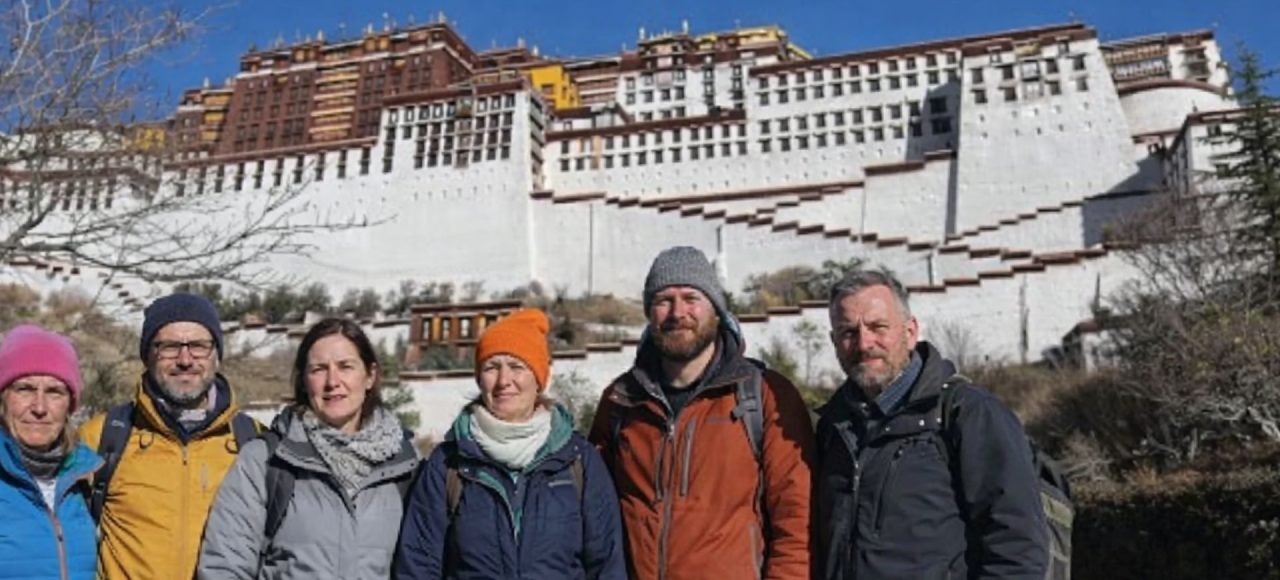 Group of trekkers standing in front of the Potala Palace during the Tibet Overland Tour from Nepal