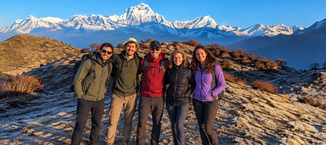 Trekkers smiling together with Mount Dhaulagiri and the Annapurna foothills in the background on the Dhaulagiri Annapurna Community Trek.