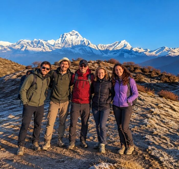 Trekkers smiling together with Mount Dhaulagiri and the Annapurna foothills in the background on the Dhaulagiri Annapurna Community Trek.
