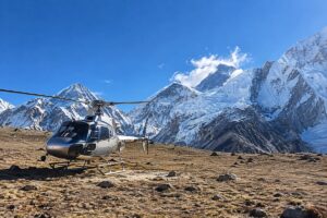 Helicopter parked on a high-altitude Himalayan plateau with snow-covered mountains