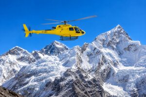 Yellow helicopter flying over the Himalayas during an Everest Base Camp helicopter tour in Nepal