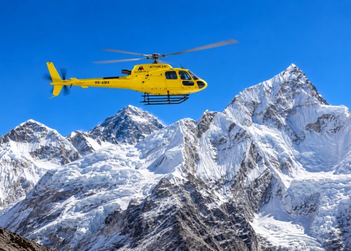 Yellow helicopter flying over the Himalayas during an Everest Base Camp helicopter tour in Nepal