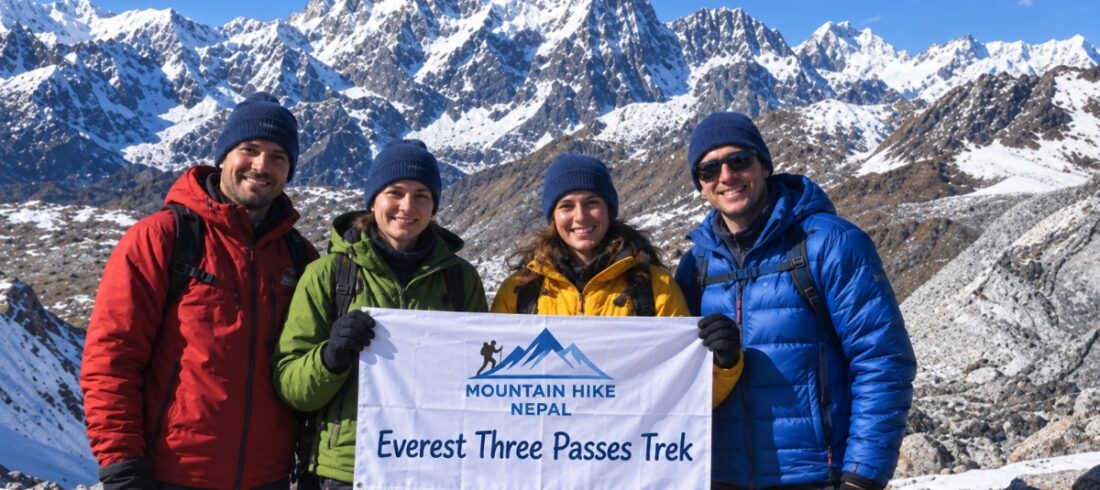 Four trekkers holding a Mountain Hike Nepal banner during the Everest Three Passes Trek in front of snowy Himalayan peaks