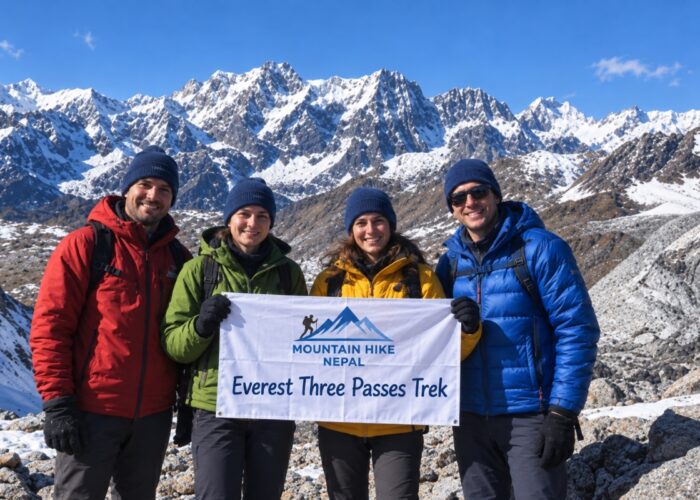 Four trekkers holding a Mountain Hike Nepal banner during the Everest Three Passes Trek in front of snowy Himalayan peaks