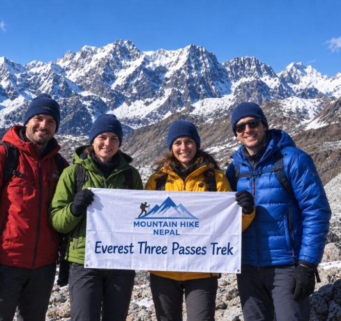 Four trekkers holding a Mountain Hike Nepal banner during the Everest Three Passes Trek in front of snowy Himalayan peaks