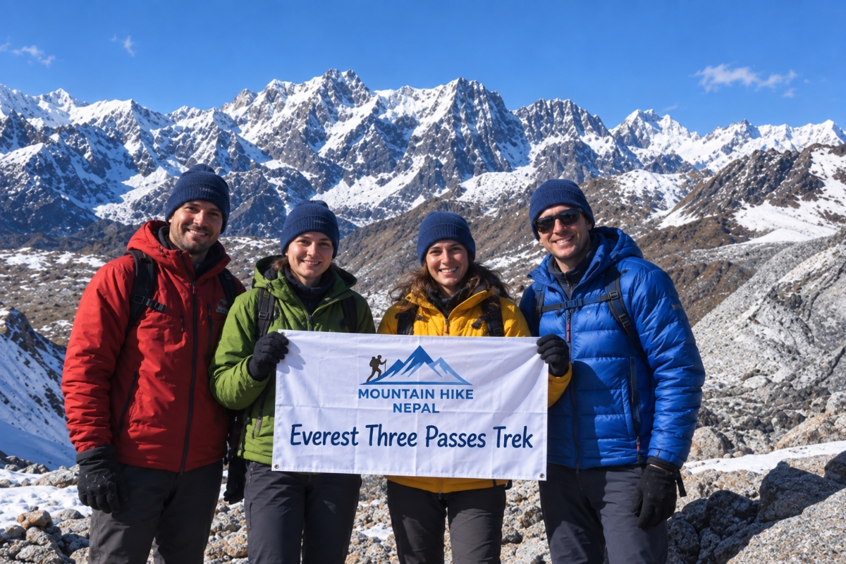 Four trekkers holding a Mountain Hike Nepal banner during the Everest Three Passes Trek in front of snowy Himalayan peaks