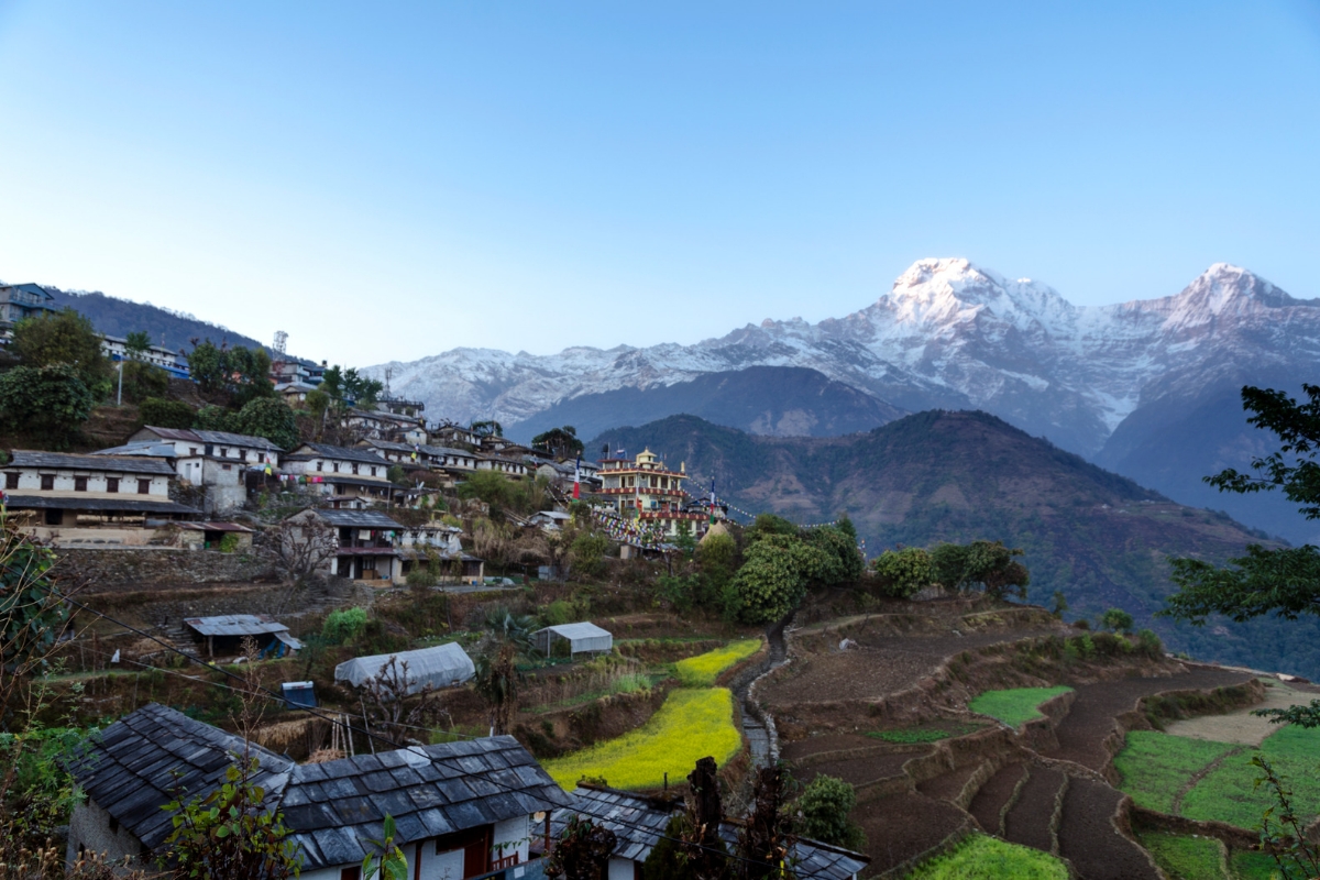 The traditional stone-roofed village of Ghandruk nestled against the massive snow-capped peaks of Annapurna South and Hiunchuli in Nepal.