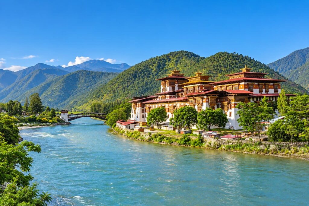 Punakha Dzong beside the river in Punakha, Bhutan, with forested mountains in the background.