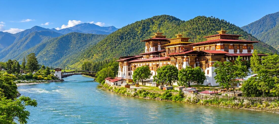 Punakha Dzong beside the river in Punakha, Bhutan, with forested mountains in the background.