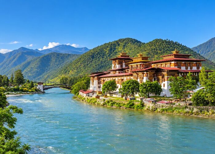 Punakha Dzong beside the river in Punakha, Bhutan, with forested mountains in the background.