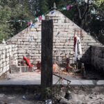 Stone shrine of the Champadevi temple among trees and prayer flags on top of Champadevi hill