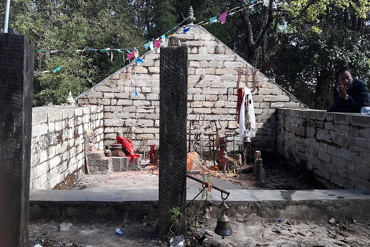 Stone shrine of the Champadevi temple among trees and prayer flags on top of Champadevi hill