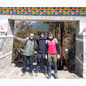 Three trekkers standing under the Pasang Lhamu Gate in Lukla, at the start of the Everest View Trek