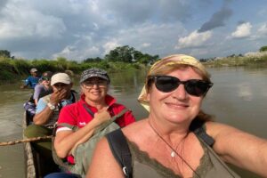 Our Guests on the Rapti River Canoe Ride Two smiling travellers in a wooden dugout canoe on the Rapti River with guides seated behind them