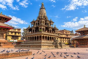 Krishna Mandir, a carved stone temple in Patan Durbar Square, with pigeons on the brick square in front