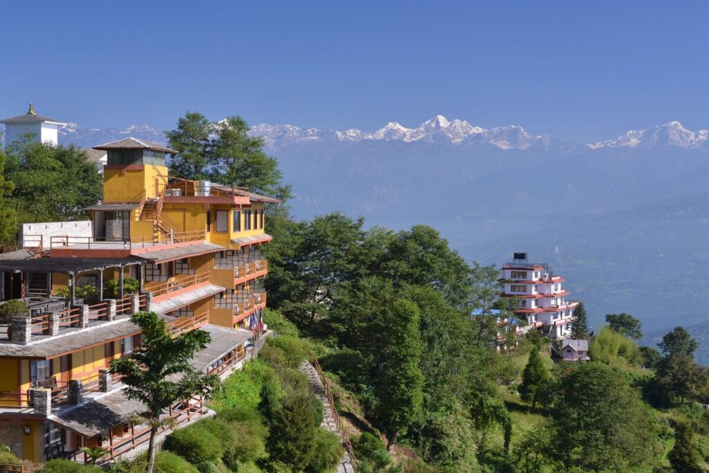Hillside hotels on the Nagarkot ridge with a snow-capped Himalayan range under a clear blue sky
