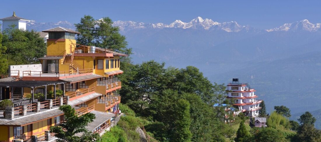 Hillside hotels on the Nagarkot ridge with a snow-capped Himalayan range under a clear blue sky