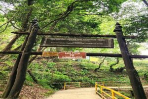 Wooden entrance gate with a Shivapuri Nagarjun National Park sign and a Welcome to Sundarijal board above a forest path