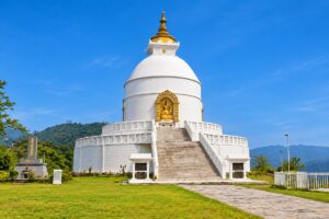 The white World Peace Pagoda in Pokhara with a golden Buddha statue above the main stairway